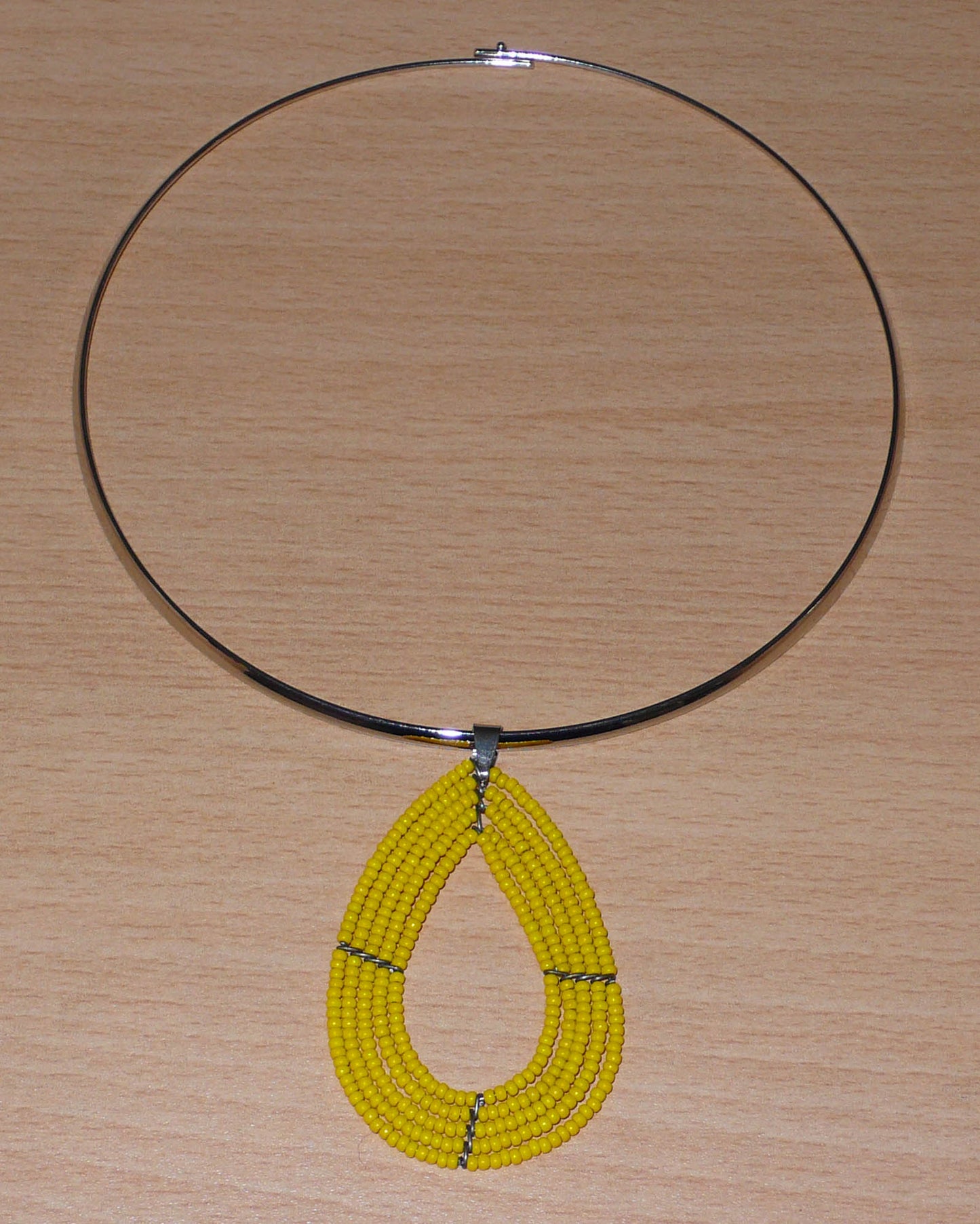 Collier jaune composé d'un ras de cou en laiton orné d'un pendentif multi-rangs fait de perles de rocaille montées en forme de goutte.