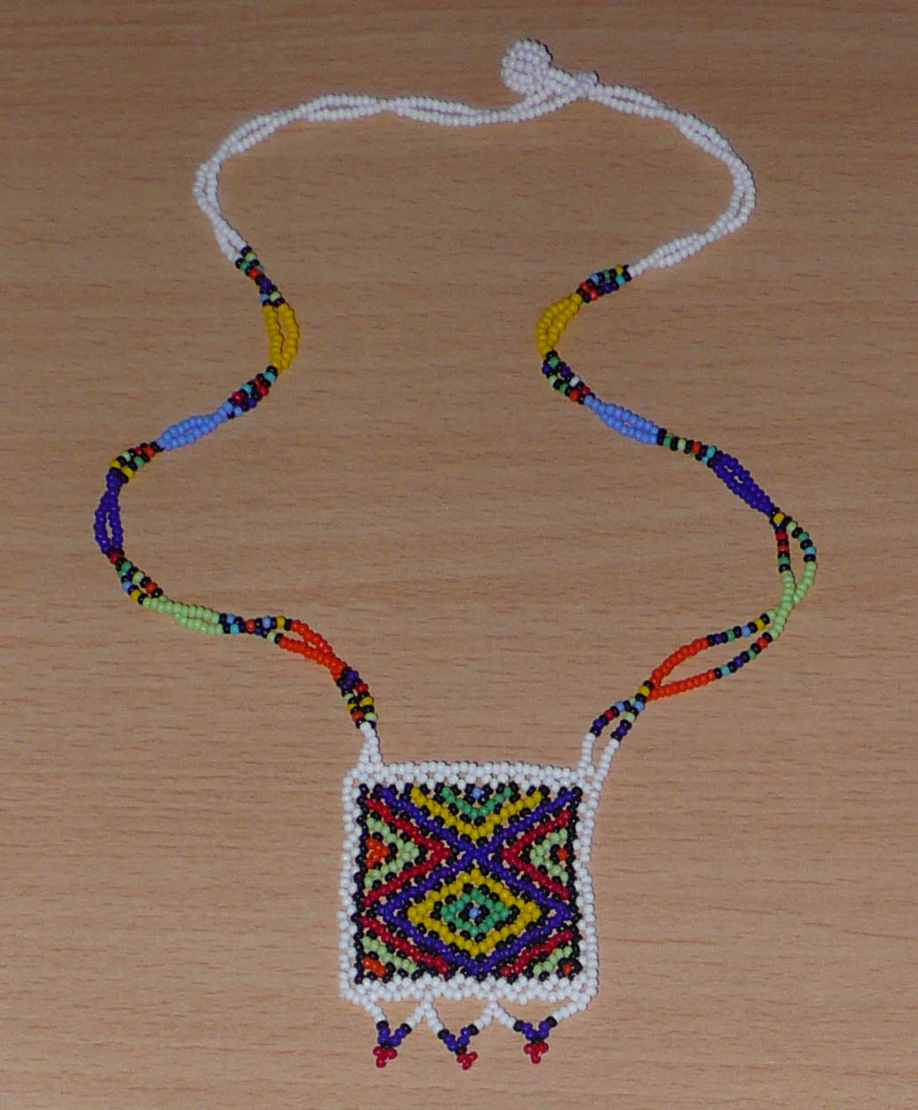 Collier africain zoulou avec pendentif ; fabriqué en Afrique du Sud, il se compose d'un tissage traditionnel de perles de rocaille blanches et multicolores.