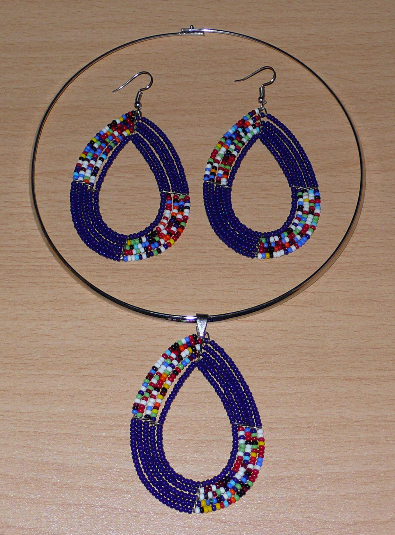 Parure de bijoux ethniques Massai comprenant un collier ras de cou orné d'un pendentif en forme de goutte fait de perles de rocaille bleu foncé et multicolores, ainsi qu'une paire de boucles d'oreilles assorties.