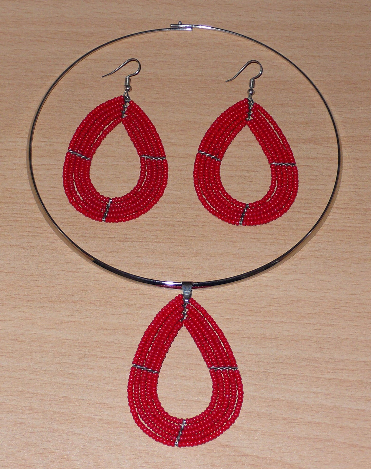 Parure de bijoux rouges composée d'un collier ras de cou en laiton agrémenté d'un pendentif multi-rangs en forme de goutte, et d'une paire de boucles d'oreilles assorties.