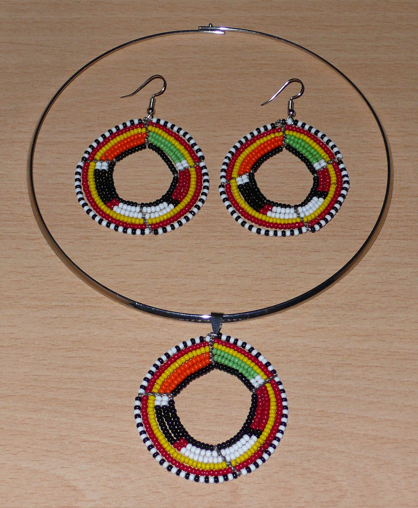 Parure de bijoux africains à motifs ethniques Massai se composant d'un ras-de-cou en laiton orné d'un pendentif rond en perles de rocaille noires et multicolores, et d'une paire de boucles d'oreilles assorties.