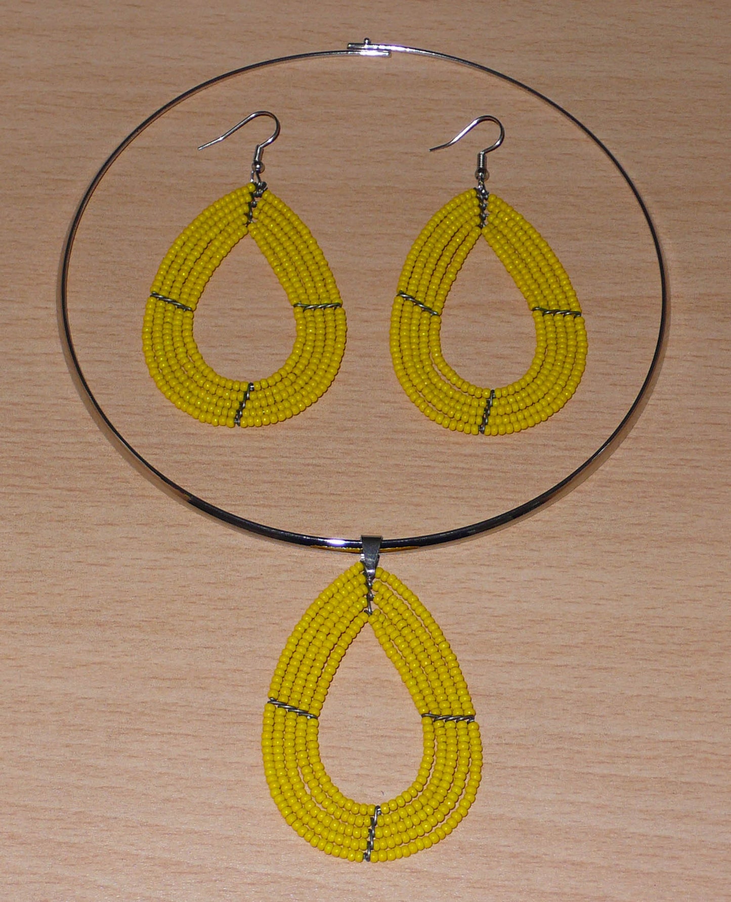 Parure de bijoux jaunes composée d'un collier ras de cou en laiton agrémenté d'un pendentif multi-rangs en forme de goutte fait de perles de rocaille, et d'une paire de boucles d'oreilles assorties.
