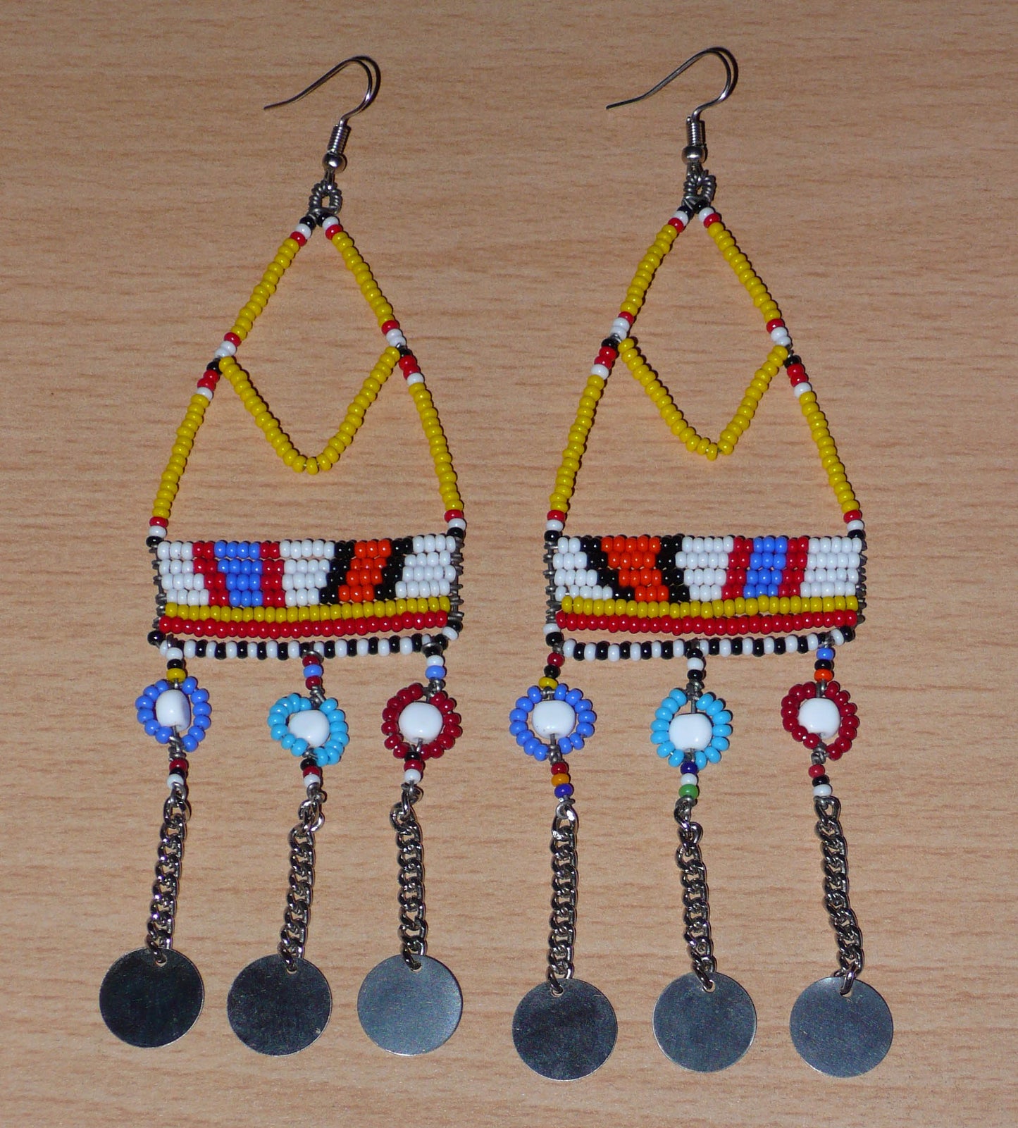 Authentiques boucles d'oreilles africaines Massai jaunes et multicolores composées de perles de rocaille, de perles en plastique et de disques métalliques. Elles mesurent 15 cm de long et se portent sur des oreilles percées.