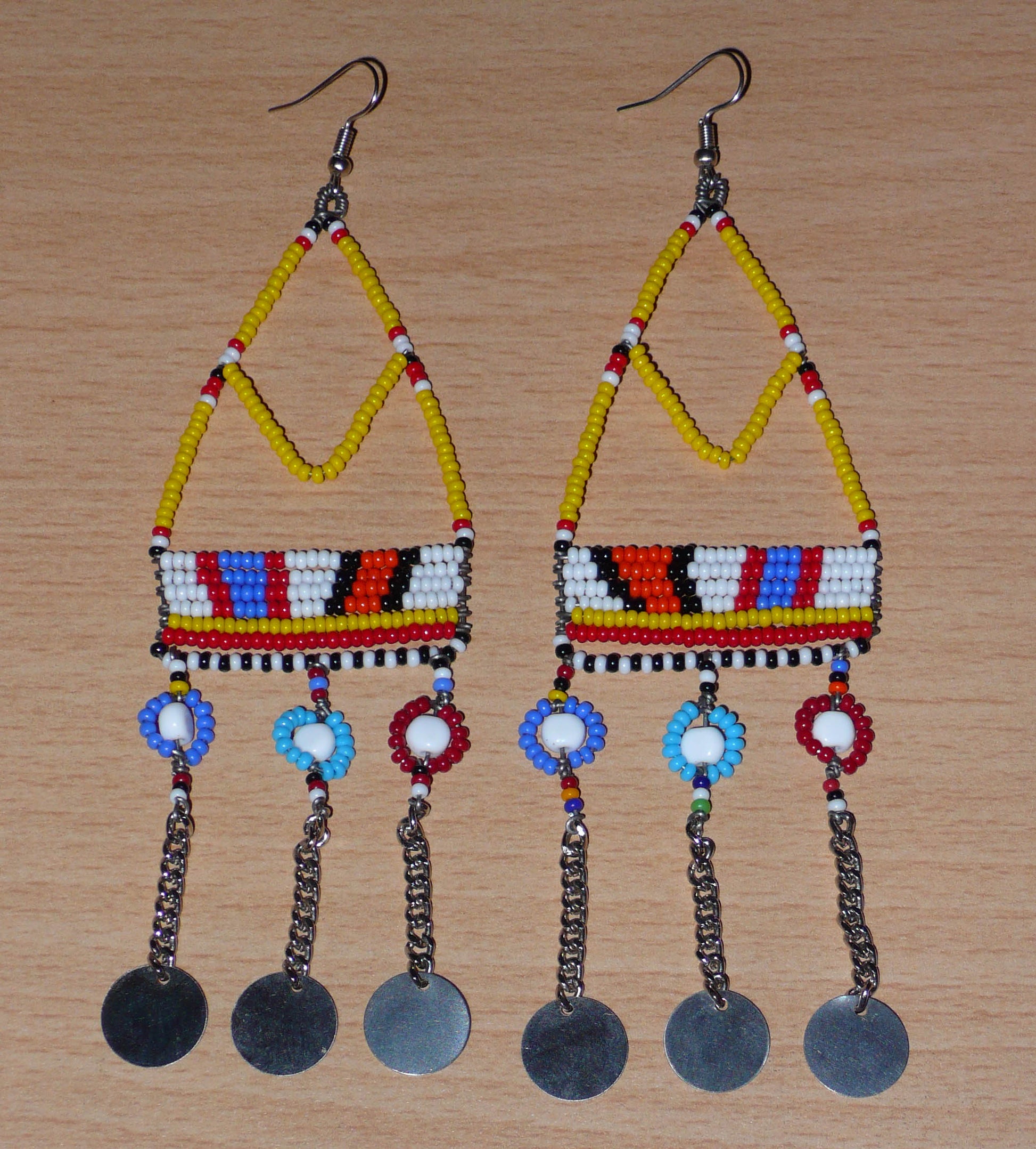 Authentiques boucles d'oreilles africaines Massai jaunes et multicolores composées de perles de rocaille, de perles en plastique et de disques métalliques. Elles mesurent 15 cm de long et se portent sur des oreilles percées.
