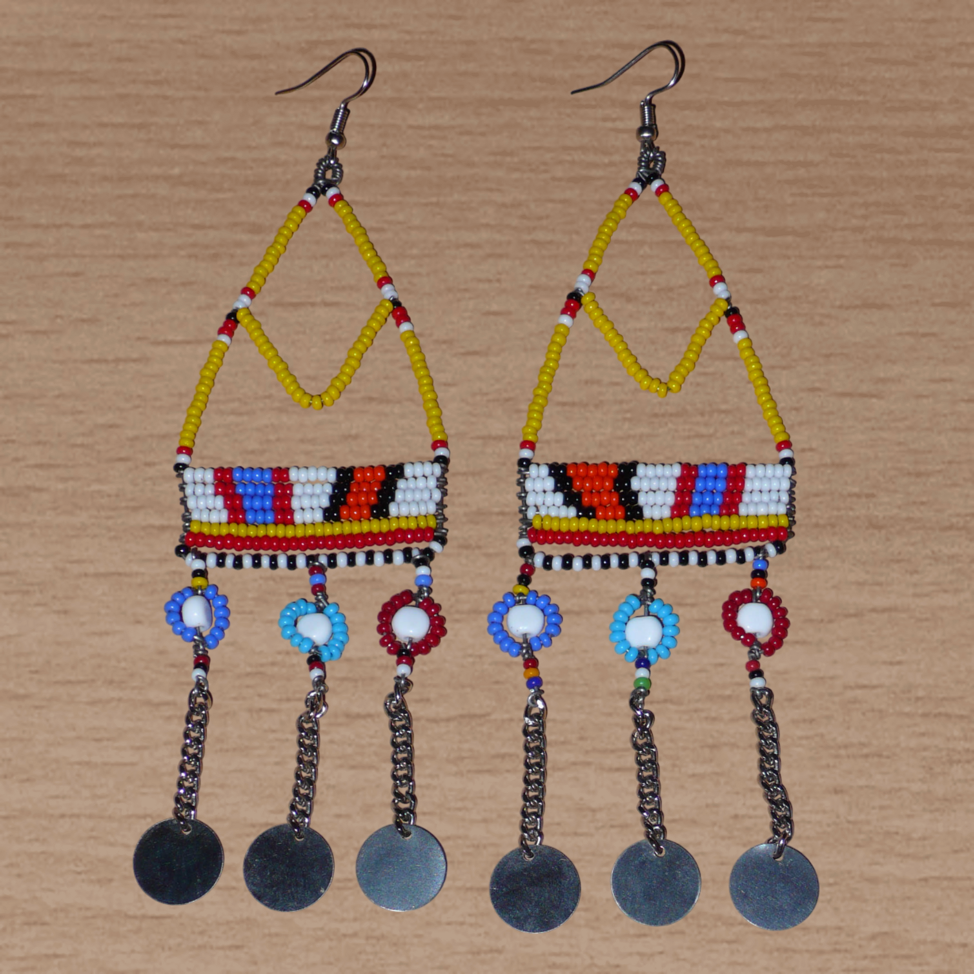 Authentiques boucles d'oreilles africaines Massai jaunes et multicolores composées de perles de rocaille, de perles en plastique et de disques métalliques. Elles mesurent 15 cm de long et se portent sur des oreilles percées.