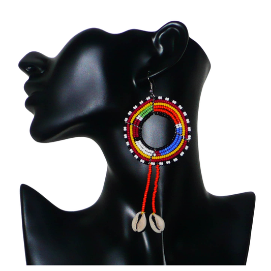 Longues boucles d'oreilles africaines Massai rondes à franges perlées, composées de perles de rocaille orange et multicolores et de coquillages cauris. Elles mesurent 12 cm de long et 5 cm de large, et se portent sur des oreilles percées.