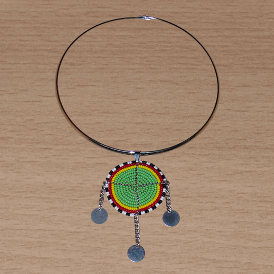 Collier africain vert composé d'un ras de cou en laiton agrémenté d'un pendentif Massai fait de perles de rocaille principalement vertes, puis rouges, jaunes, noires et blanches, et prolongé de trois chaînettes ornées de pastilles métalliques.