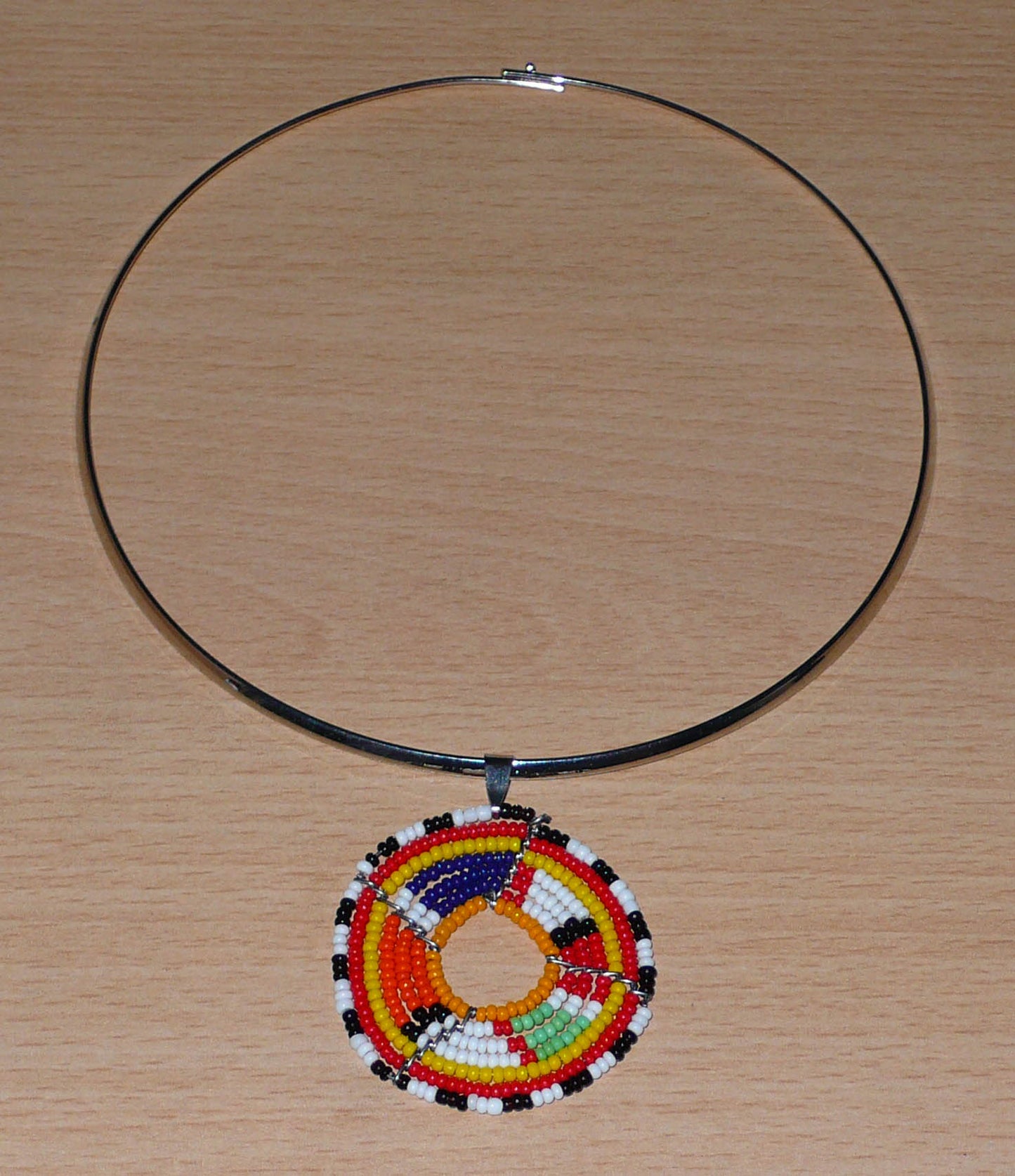 Collier africain composé d'un ras-de-cou en laiton orné d'un médaillon composé de perles de rocaille multicolores. 
