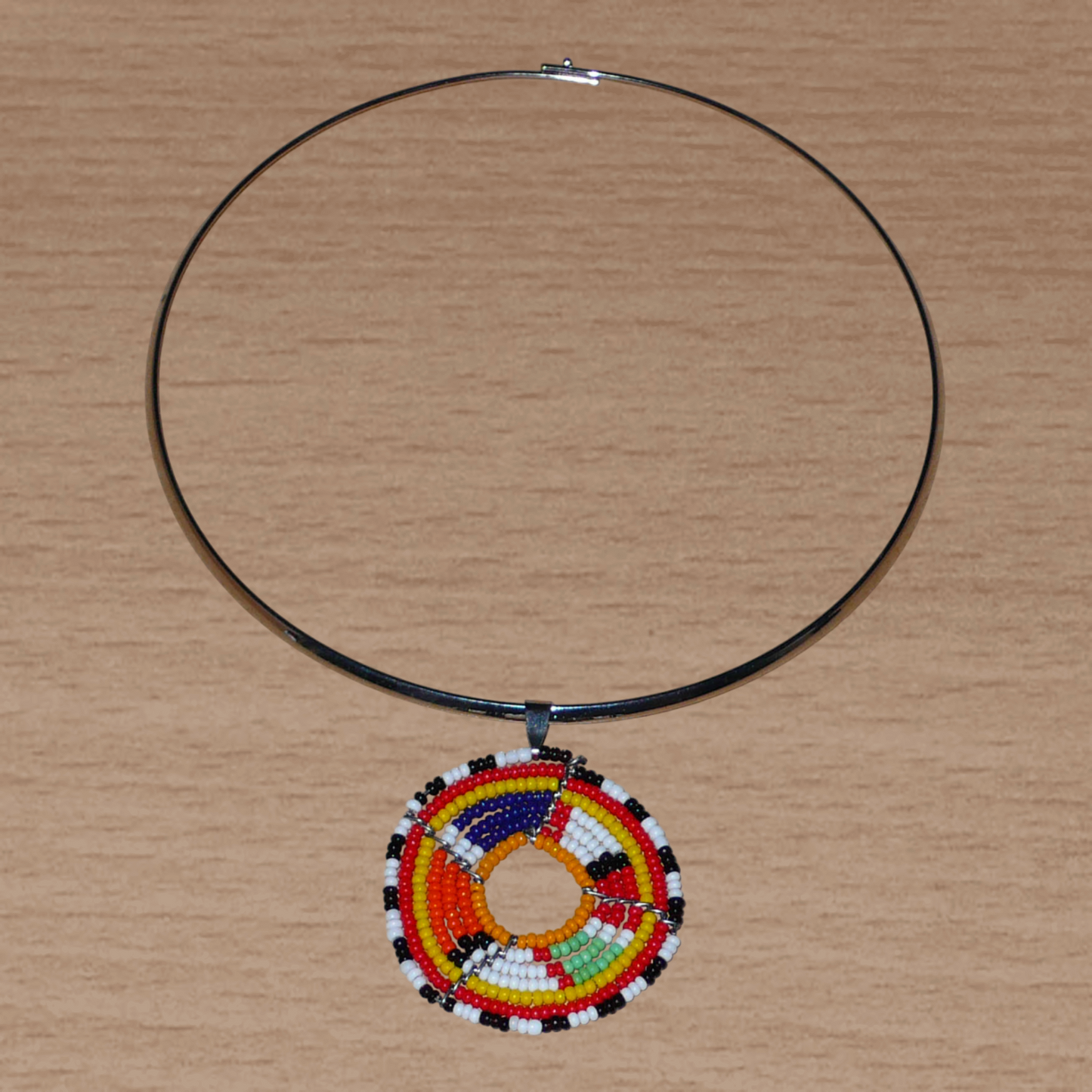 Collier africain composé d'un ras de cou en laiton orné d'un médaillon fait de perles de rocaille multicolores. 