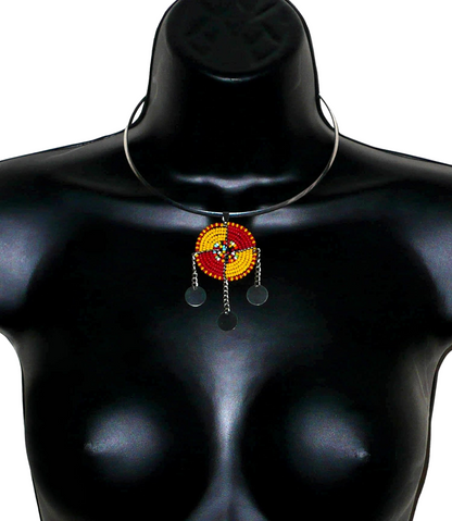 Bijou africain se composant d'un collier ras de cou en laiton rehaussé d'un pendentif Massai rond fait de perles de rocaille rouges, jaunes et multicolores, et prolongé de trois chaînettes ornées de disques métalliques.