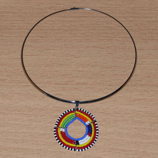 Collier africain composé d'un ras de cou en laiton agrémenté d'un médaillon aux couleurs et motifs ethniques Massai fait de perles de rocaille multicolores.