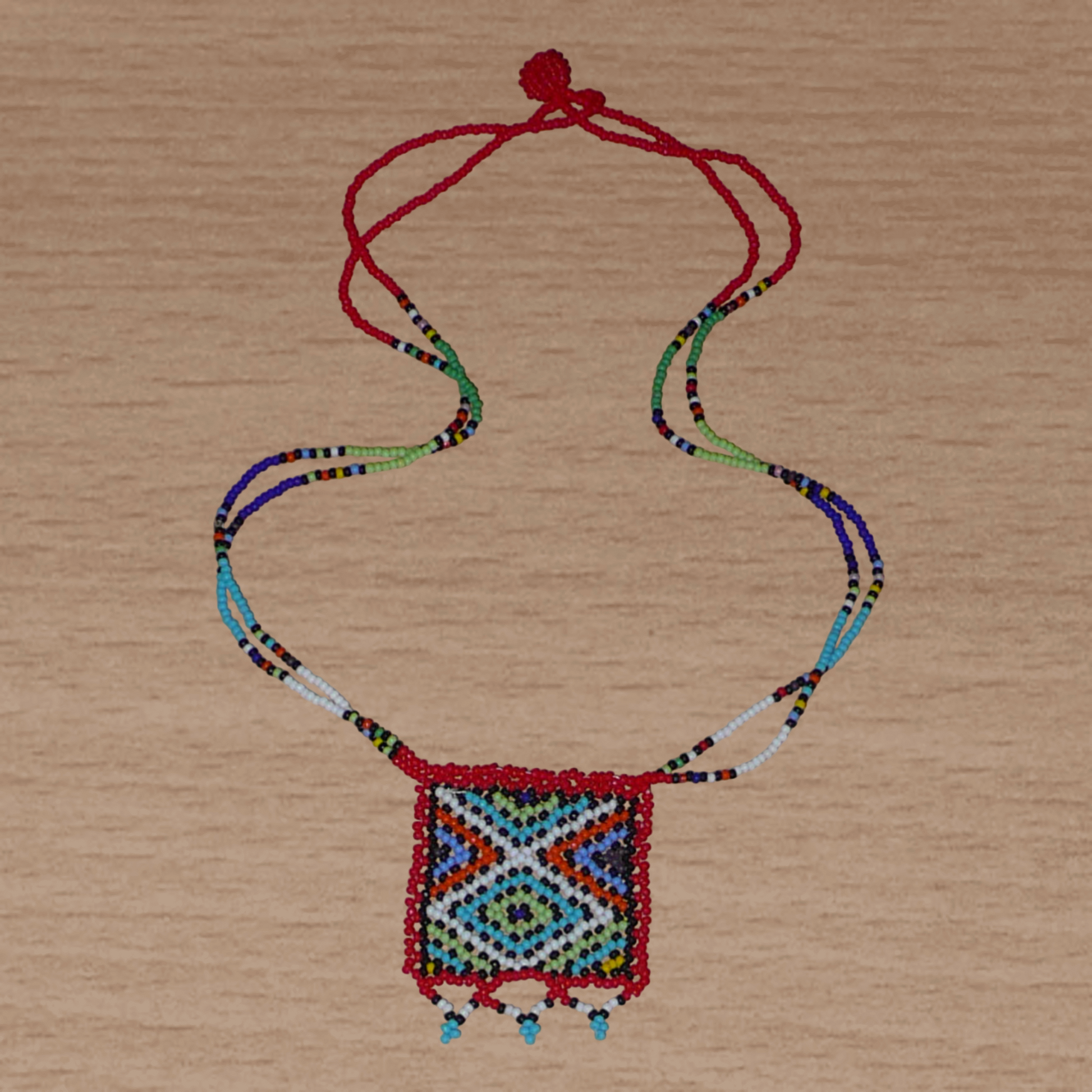 Collier africain traditionnel zoulou avec pendentif carré à motifs ethniques en perles de rocaille rouges et multicolores.