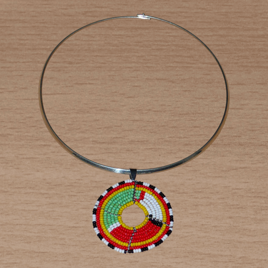 Collier africain composé d'un ras de cou en laiton agrémenté d'un médaillon ethnique aux couleurs et motifs traditionnels Massai fait de perles de rocaille multicolores.