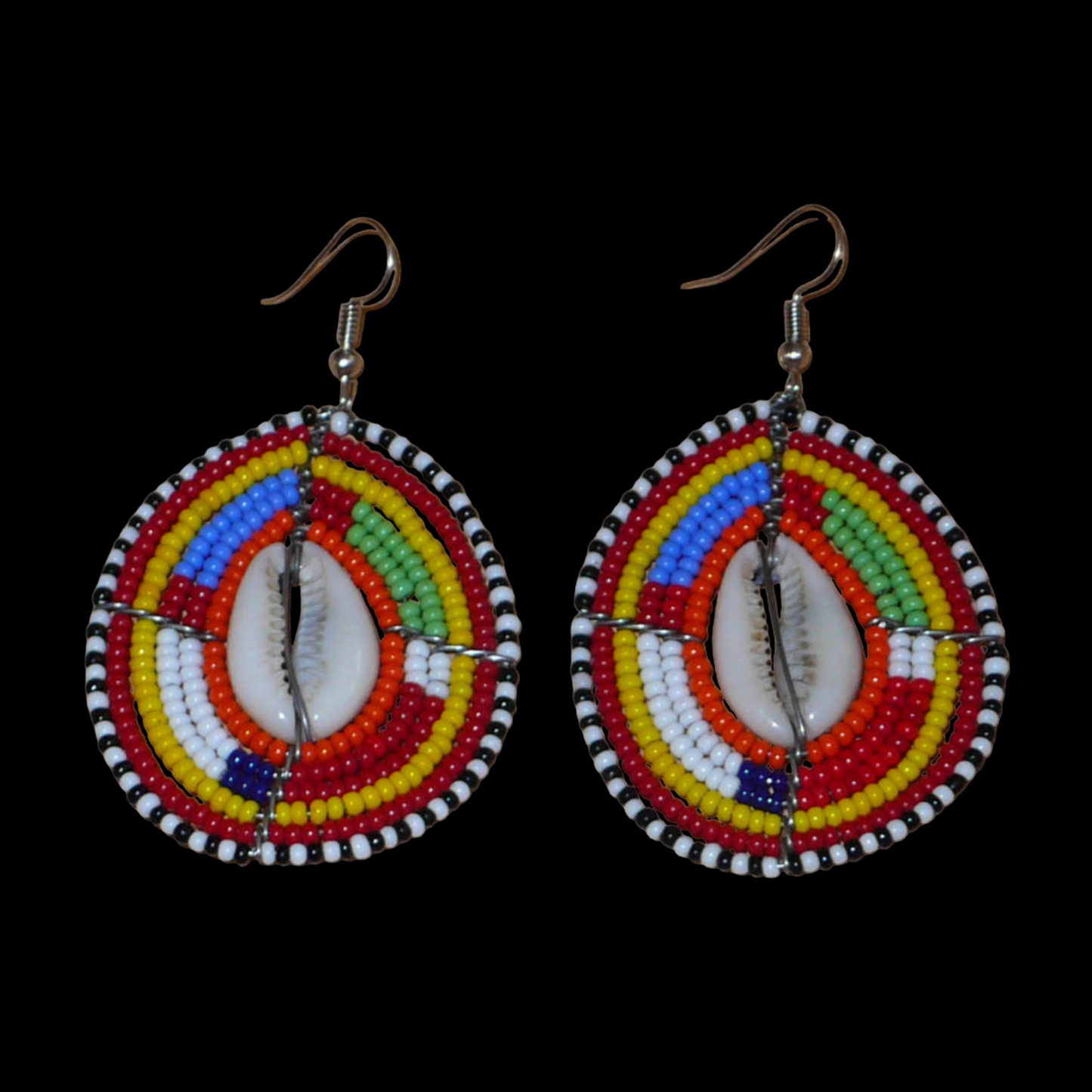 Boucles d'oreilles africaines ethniques composées de perles multicolores et de cauris montés en forme de boucliers Massai.  Elles mesurent 7 cm de long et 4 cm de large et se portent sur des oreilles percées.