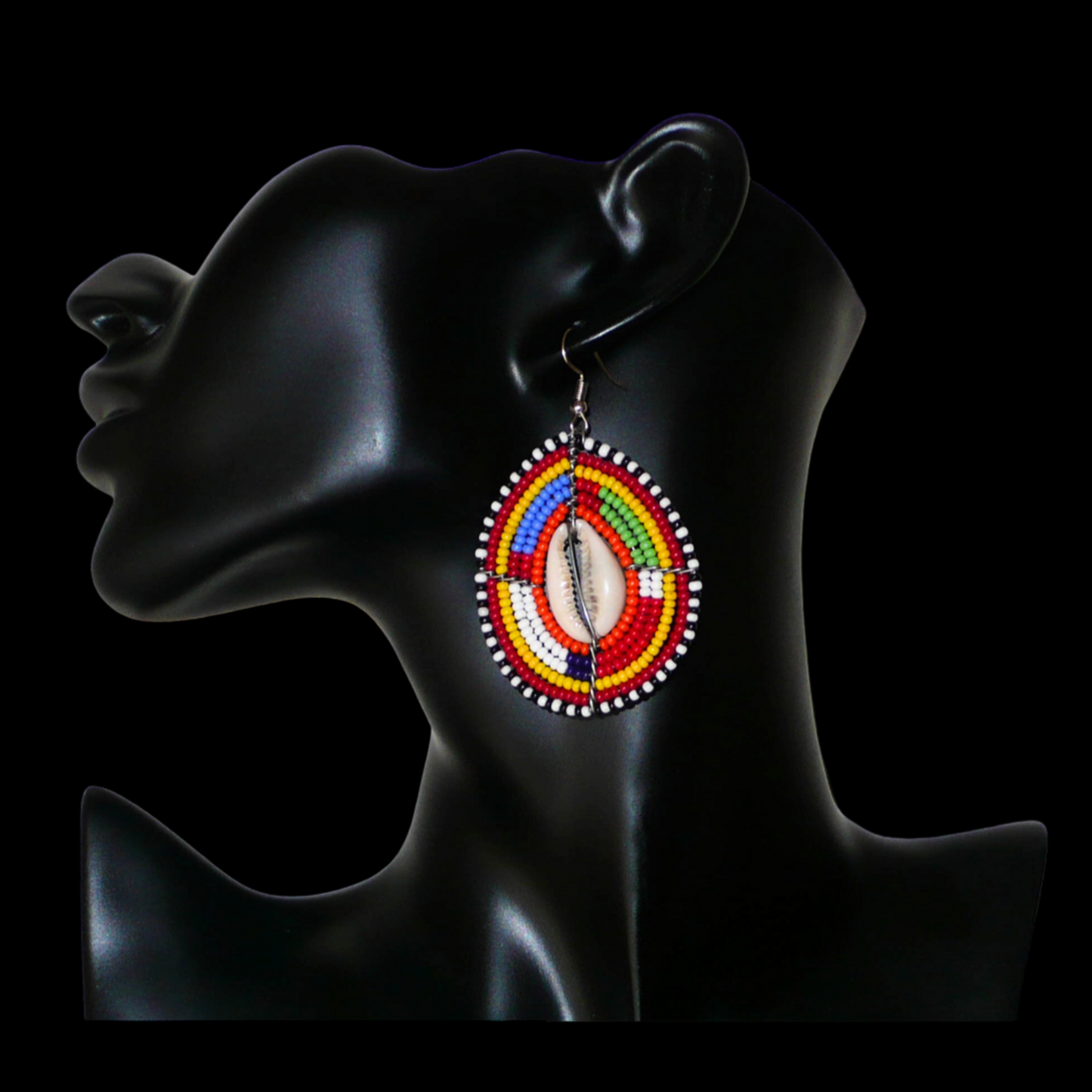 Boucles d'oreilles africaines ethniques composées de perles multicolores et de cauris montés en forme de boucliers Massai.  Elles mesurent 7 cm de long et 4 cm de large et se portent sur des oreilles percées.