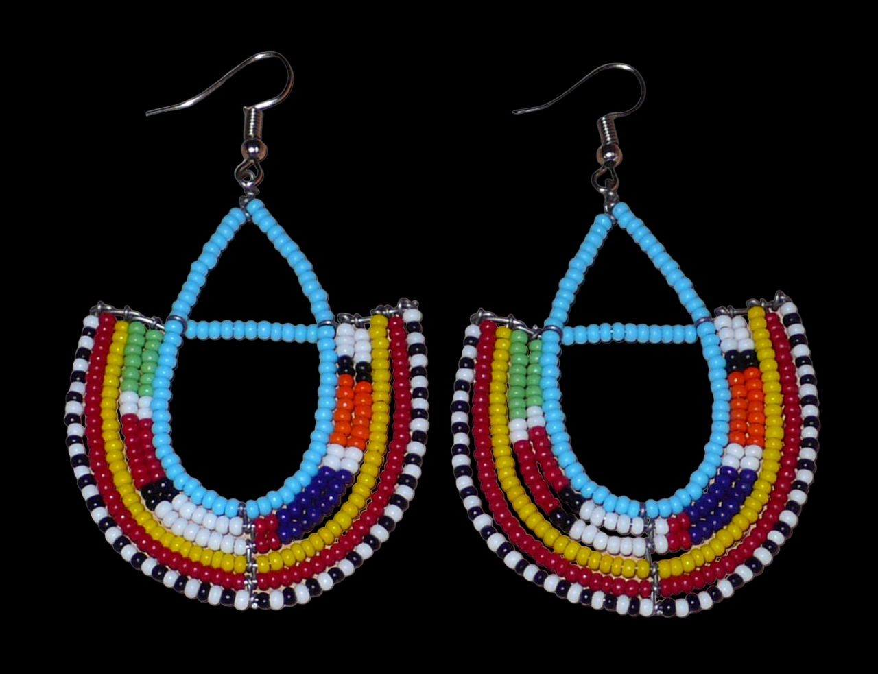 Boucles d'oreilles africaines à motifs ethniques Massai fabriquées au Kenya. Elles se composent de perles de rocaille bleu ciel et multicolores montées en forme d'ancres. Ces boucles d'oreilles afro chic mesurent 7,5 cm de long et 4,5 cm de large. Elles se portent avec des crochets en acier inoxydable sur des oreilles percées.