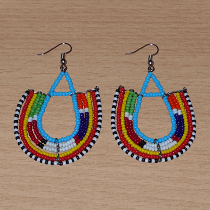Boucles d'oreilles africaines traditionnelles à motifs ethniques Massai composées de perles de rocaille bleues et multicolores enfilées sur des fils de fer montés en forme d'ancres.

Ces boucles d'oreilles colorées au style exotique tribal chic mesurent 7.5 cm de long et 4.5 cm de large, elles se portent avec des crochets en acier inoxydable sur des oreilles percées.