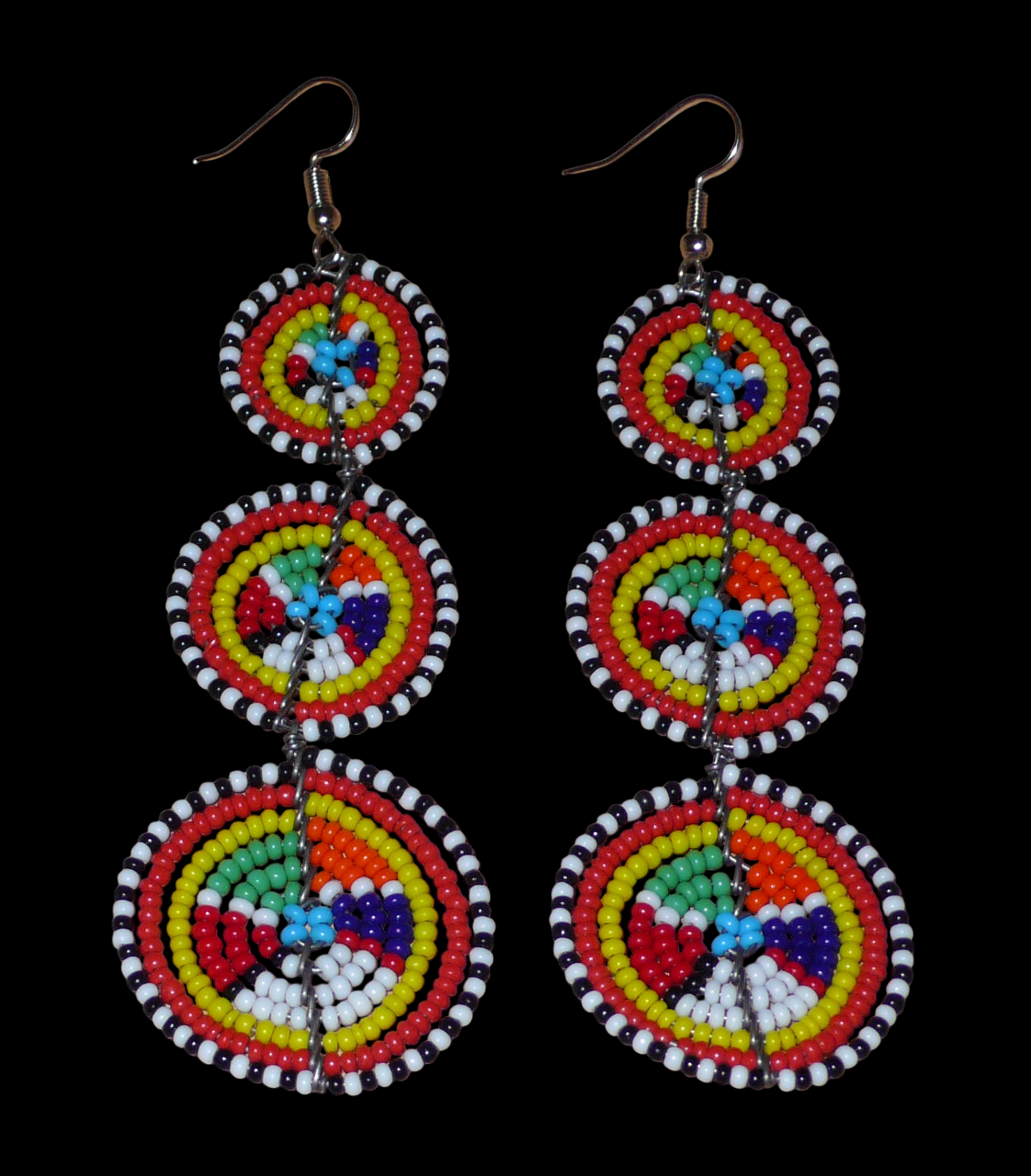 Ajoutez une touche colorée à votre look, évocatrice du style afro chic des années 70, avec ces boucles d'oreilles africaines traditionnelles de confection artisanale Massai. Elles se composent de perles de rocaille multicolores glissées sur des fils de fer montés en forme de trois cercles superposés. Ces boucles d'oreilles mesurent 10.5 cm de long et 3 cm de large ; elles se portent avec des crochets en acier inoxydable sur des oreilles percées.