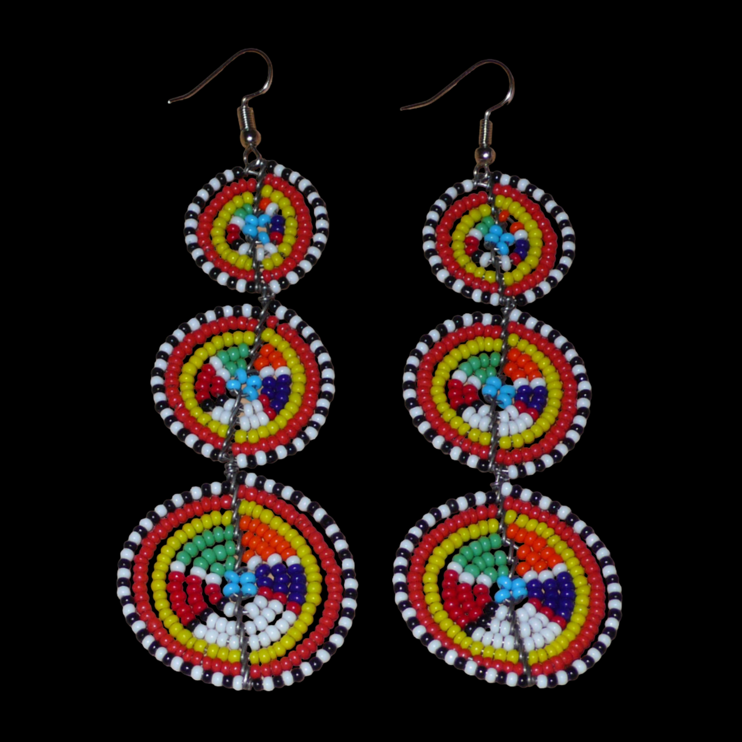Ajoutez une touche colorée à votre look, évocatrice du style afro chic des années 70, avec ces boucles d'oreilles africaines traditionnelles de confection artisanale Massai. Elles se composent de perles de rocaille multicolores glissées sur des fils de fer montés en forme de trois cercles superposés. Ces boucles d'oreilles mesurent 10.5 cm de long et 3 cm de large ; elles se portent avec des crochets en acier inoxydable sur des oreilles percées.