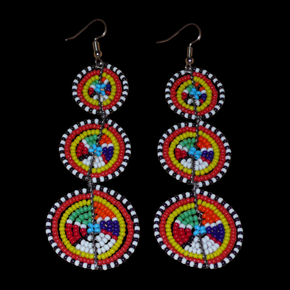 Ajoutez une touche colorée à votre look, évocatrice du style afro chic des années 70, avec ces boucles d'oreilles africaines traditionnelles de confection artisanale Massai. Elles se composent de perles de rocaille multicolores glissées sur des fils de fer montés en forme de trois cercles superposés. Ces boucles d'oreilles mesurent 10.5 cm de long et 3 cm de large ; elles se portent avec des crochets en acier inoxydable sur des oreilles percées.