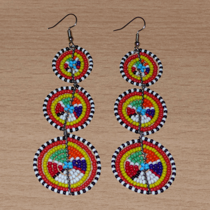 Ajoutez une touche colorée à votre look, évocatrice du style afro chic des années 70, avec ces boucles d'oreilles africaines traditionnelles de confection artisanale Massai. Elles se composent de perles de rocaille multicolores glissées sur des fils de fer montés en forme de trois cercles superposés. Ces boucles d'oreilles mesurent 10.5 cm de long et 3 cm de large ; elles se portent avec des crochets en acier inoxydable sur des oreilles percées.