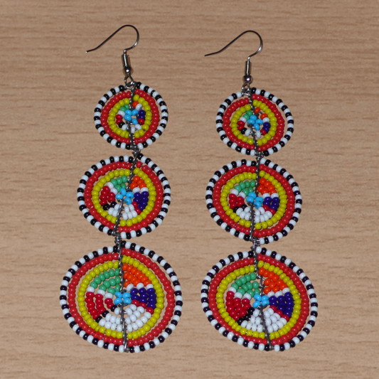 Ajoutez une touche colorée à votre look, évocatrice du style afro chic des années 70, avec ces boucles d'oreilles africaines traditionnelles de confection artisanale Massai. Elles se composent de perles de rocaille multicolores glissées sur des fils de fer montés en forme de trois cercles superposés. Ces boucles d'oreilles mesurent 10.5 cm de long et 3 cm de large ; elles se portent avec des crochets en acier inoxydable sur des oreilles percées.