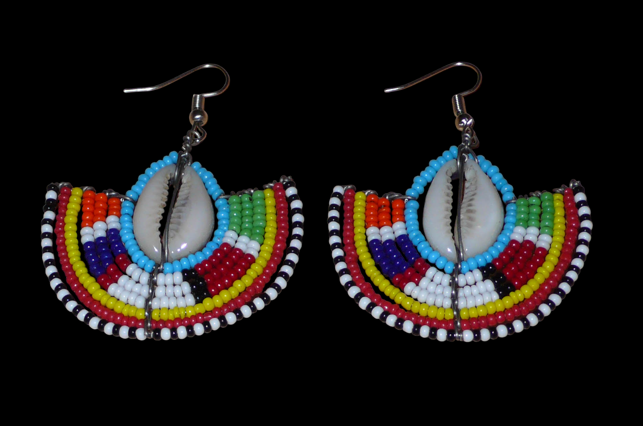 Affirmez votre style et apportez une touche exotique à votre look avec cette paire de boucles d'oreilles africaines Massai issues de l'artisanat traditionnel kenyan. Ces boucles d'oreilles aux accents ethniques chic se composent de perles de rocaille bleues et multicolores et de coquillages cauris. De taille moyenne, elles mesurent 6 cm de long et 4.5 cm de large, et se portent avec des crochets en acier inoxydable sur des oreilles percées.
