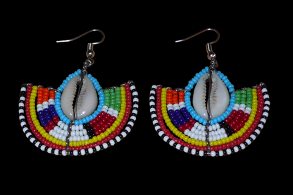 Affirmez votre style et apportez une touche exotique à votre look avec cette paire de boucles d'oreilles africaines Massai issues de l'artisanat traditionnel kenyan. Ces boucles d'oreilles aux accents ethniques chic se composent de perles de rocaille bleues et multicolores et de coquillages cauris. De taille moyenne, elles mesurent 6 cm de long et 4.5 cm de large, et se portent avec des crochets en acier inoxydable sur des oreilles percées.