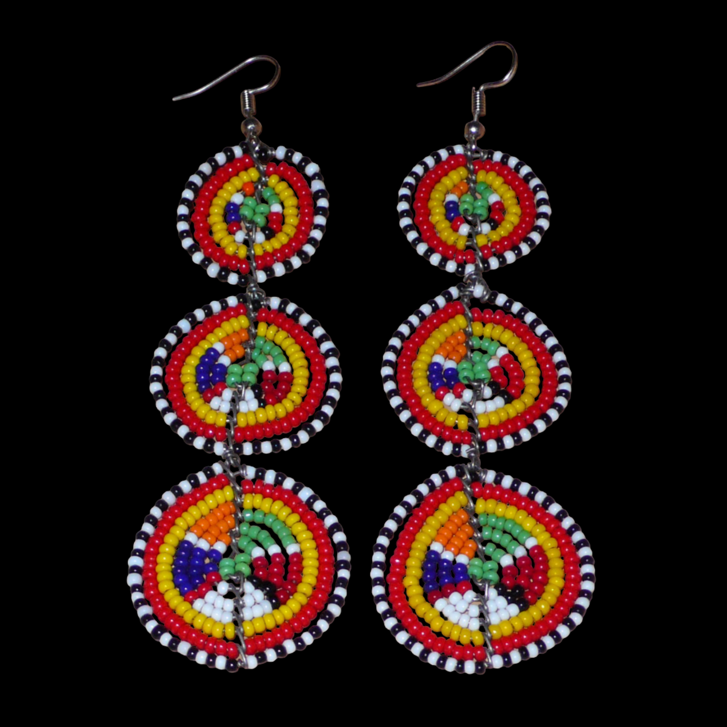 Affirmez votre style avec ces boucles d'oreilles africaines traditionnelles de confection artisanale Massai, évoquant le style afro chic des années 70. Elles se composent de perles de rocaille multicolores enfilées sur des fils de fer montés en forme de trois cercles superposés. Ces boucles d'oreilles mesurent 11 cm de long et 3.5 cm de large ; elles se portent avec des crochets en acier inoxydable sur des oreilles percées.