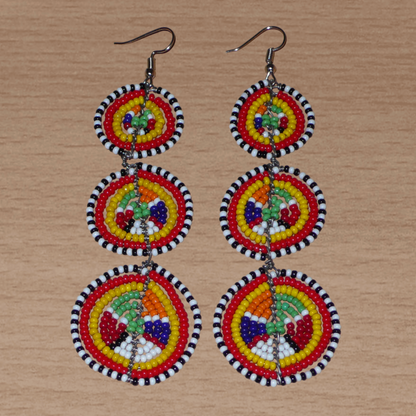 Affirmez votre style avec ces boucles d'oreilles africaines traditionnelles de confection artisanale Massai, évoquant le style afro chic des années 70. Elles se composent de perles de rocaille multicolores enfilées sur des fils de fer montés en forme de trois cercles superposés. Ces boucles d'oreilles mesurent 11 cm de long et 3.5 cm de large ; elles se portent avec des crochets en acier inoxydable sur des oreilles percées.