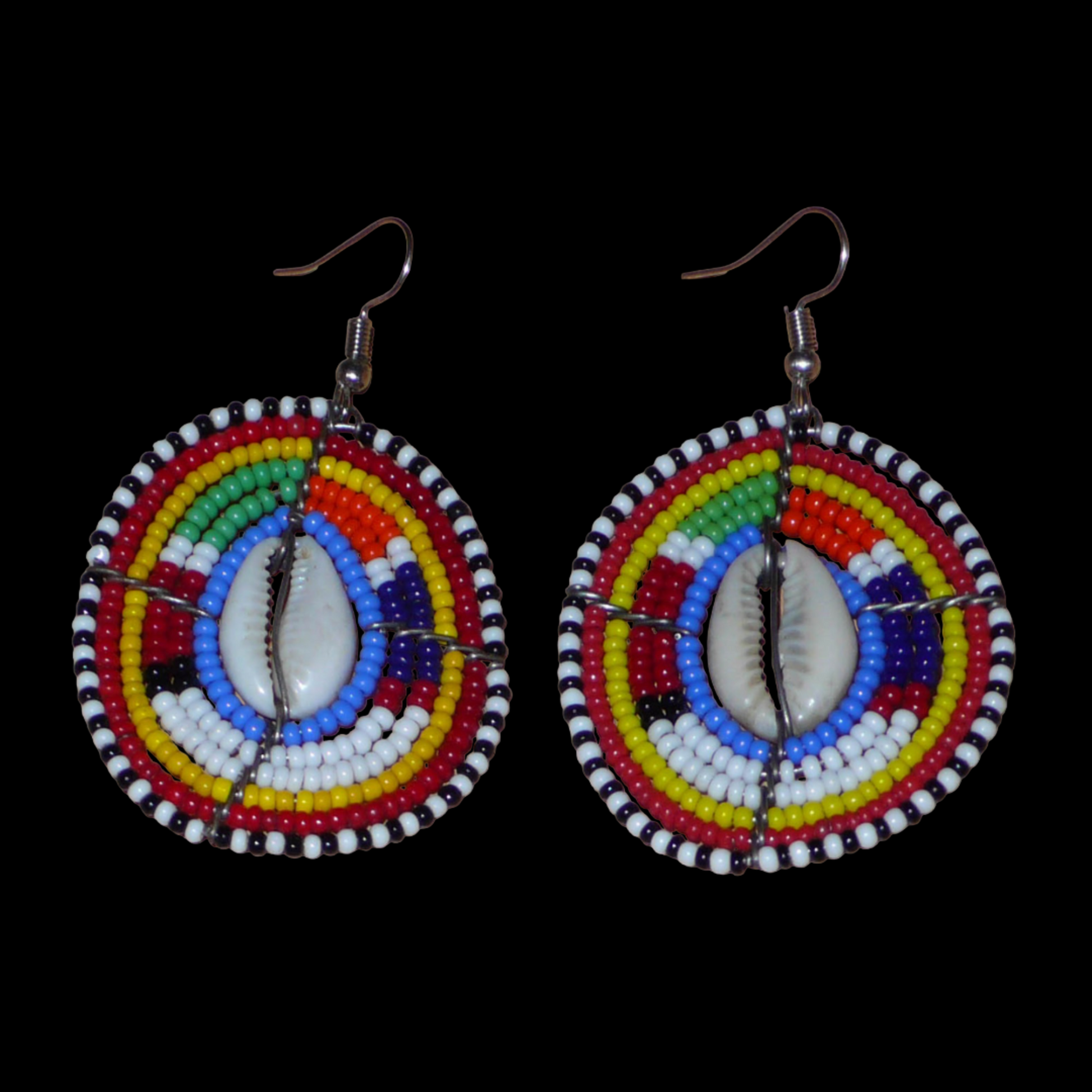 Boucles d'oreilles africaines traditionnelles, aux couleurs et motifs ethniques Massai, de fabrication artisanale kenyane. Elles se composent de perles de rocaille bleues et multicolores et de coquillages cauris fixés sur des fils de fer montés en forme de boucliers Massai. Ces boucles d'oreilles de taille moyenne mesurent 6.5 cm de long et 4 cm de large ; elles se portent avec des crochets en acier inoxydable sur des oreilles percées.