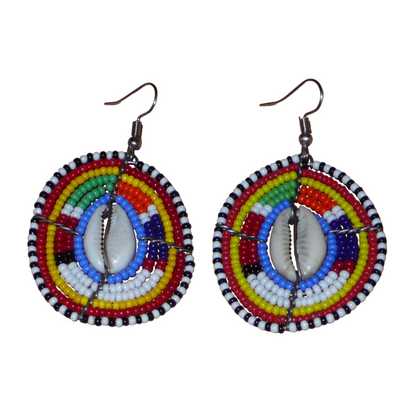 Boucles d'oreilles africaines traditionnelles, aux couleurs et motifs ethniques Massai, de fabrication artisanale kenyane. Elles se composent de perles de rocaille bleues et multicolores et de coquillages cauris fixés sur des fils de fer montés en forme de boucliers Massai. Ces boucles d'oreilles de taille moyenne mesurent 6.5 cm de long et 4 cm de large ; elles se portent avec des crochets en acier inoxydable sur des oreilles percées.