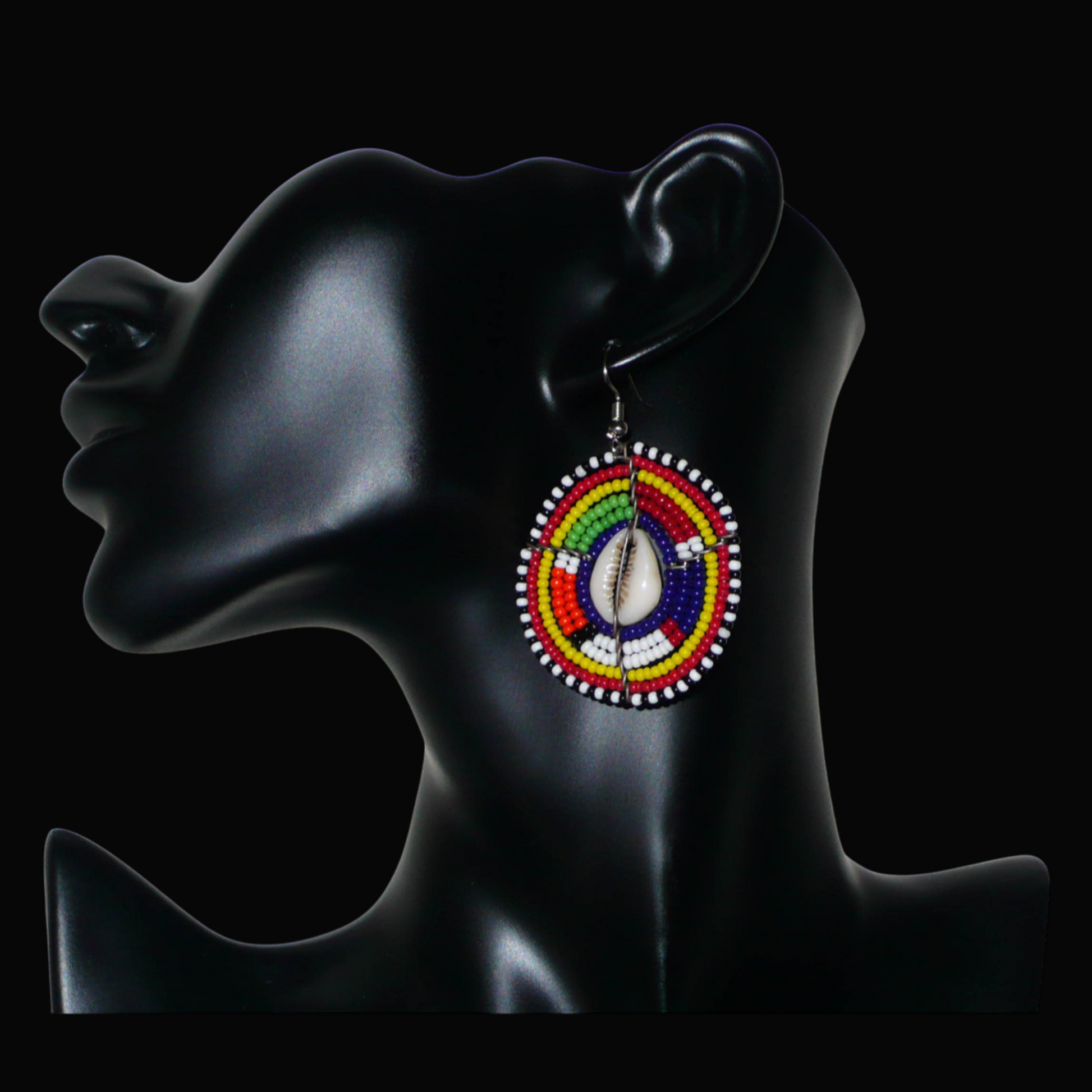 Boucles d'oreilles africaines traditionnelles aux motifs ethniques caractéristiques de l'artisanat Massai. De fabrication kenyane, elles se composent de perles de rocaille bleu foncé et multicolores et de cauris fixés sur des fils de fer montés en forme de boucliers Massai. Ces boucles d'oreilles de taille moyenne mesurent 6 cm de long et 4 cm de large ; elles se portent avec des crochets en acier inoxydable sur des oreilles percées.