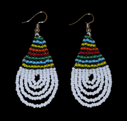 Boucles d'oreilles africaines à motifs traditionnels zoulous en forme de gouttes composées d'un tissage de perles de rocaille blanches et multicolores. Elles mesurent 7 cm de long et 2,5 cm de large et se portent sur des oreilles percées.