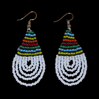 Boucles d'oreilles africaines à motifs traditionnels zoulous en forme de gouttes composées d'un tissage de perles de rocaille blanches et multicolores. Elles mesurent 7 cm de long et 2,5 cm de large et se portent sur des oreilles percées.