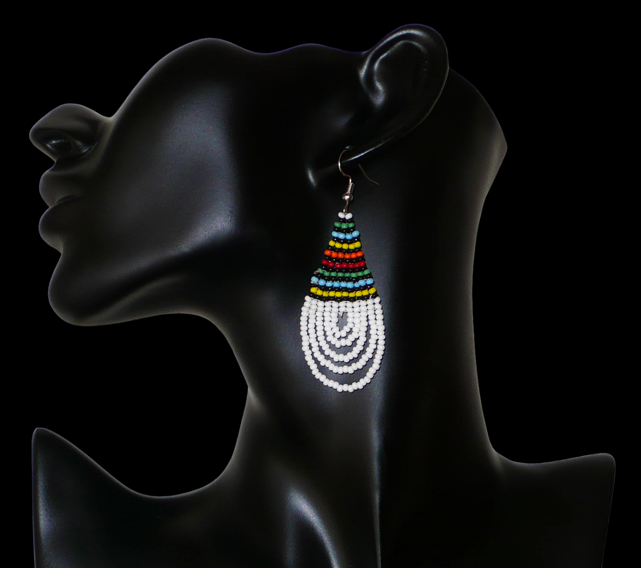 Boucles d'oreilles africaines à motifs traditionnels zoulous en forme de gouttes composées d'un tissage de perles de rocaille blanches et multicolores. Elles mesurent 7 cm de long et 2,5 cm de large et se portent sur des oreilles percées. Timeless Fineries