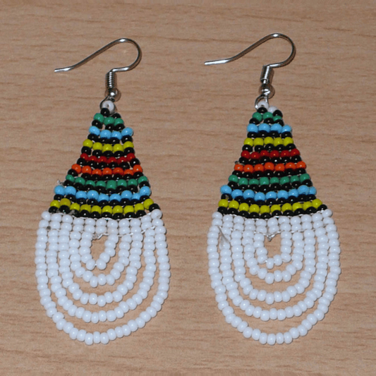 Boucles d'oreilles africaines à motifs traditionnels zoulous en forme de gouttes composées d'un tissage de perles de rocaille blanches et multicolores. Elles mesurent 7 cm de long et 2,5 cm de large et se portent sur des oreilles percées.