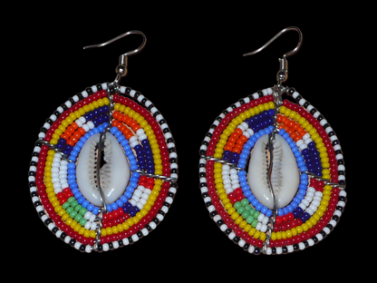 Boucles d'oreilles africaines en forme de boucliers Massai composées de perles de rocaille multicolores et de coquillages cauris. Elles mesurent 7 cm de long et 4 cm de large.