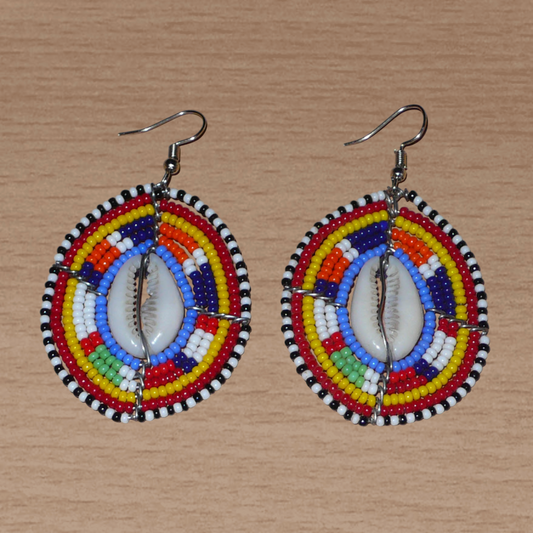 Boucles d'oreilles africaines en forme de boucliers Massai composées de perles de rocaille multicolores et de coquillages cauris. Elles mesurent 7 cm de long et 4 cm de large.