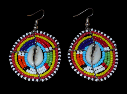 Boucles d'oreilles africaines traditionnelles aux motifs ethniques caractéristiques de l'artisanat Massai. De fabrication kenyane, elles se composent de perles de rocaille bleues et multicolores et de coquillages fixés sur des fils de fer montés en forme de boucliers Massai. Ces boucles d'oreilles de taille moyenne mesurent 6.5 cm de long et 4 cm de large ; elles se portent avec des crochets en acier inoxydable sur des oreilles percées.