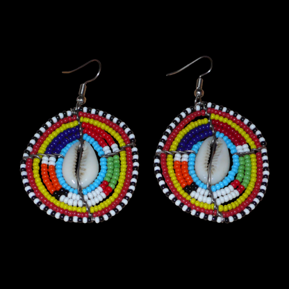 Boucles d'oreilles africaines traditionnelles aux motifs ethniques caractéristiques de l'artisanat Massai. De fabrication kenyane, elles se composent de perles de rocaille bleues et multicolores et de coquillages fixés sur des fils de fer montés en forme de boucliers Massai. Ces boucles d'oreilles de taille moyenne mesurent 6.5 cm de long et 4 cm de large ; elles se portent avec des crochets en acier inoxydable sur des oreilles percées.
