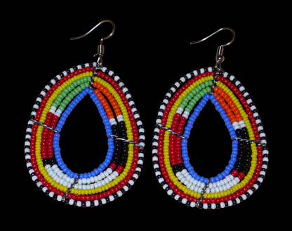 Boucles d'oreilles ethniques multi-rangs à motifs traditionnels Massai composées de perles de rocaille bleues et multicolores glissées sur six rangs de fils de fer montés en forme de gouttes. Elles mesurent 7.5 cm de long et 4 cm de large, et se portent avec des crochets en acier inoxydable sur des oreilles percées.