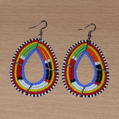 Boucles d'oreilles ethniques multi-rangs à motifs traditionnels Massai composées de perles de rocaille bleues et multicolores glissées sur six rangs de fils de fer montés en forme de gouttes. Elles mesurent 7.5 cm de long et 4 cm de large, et se portent avec des crochets en acier inoxydable sur des oreilles percées.