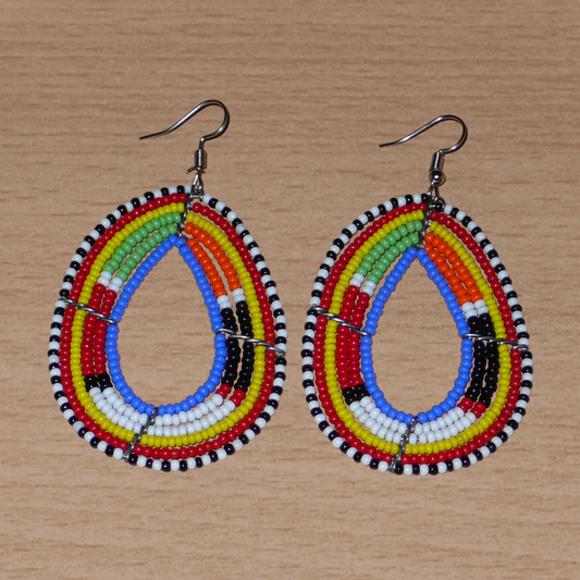 Boucles d'oreilles ethniques multi-rangs à motifs traditionnels Massai composées de perles de rocaille bleues et multicolores glissées sur six rangs de fils de fer montés en forme de gouttes. Elles mesurent 7.5 cm de long et 4 cm de large, et se portent avec des crochets en acier inoxydable sur des oreilles percées.