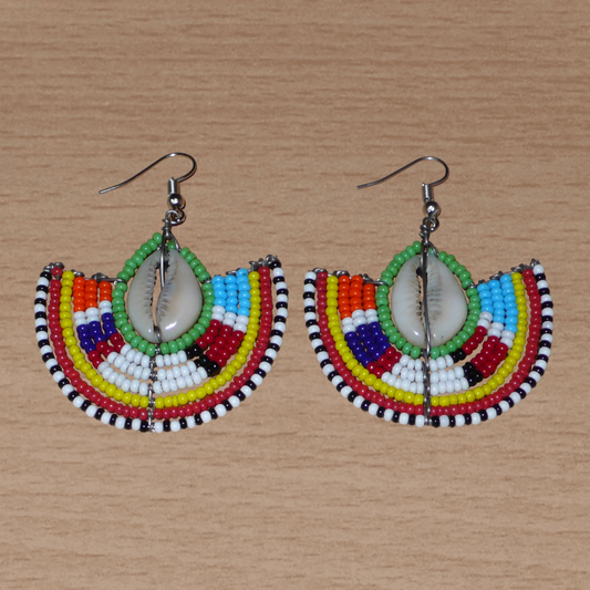 Ajoutez une touche afro chic à votre style avec cette jolie paire de boucles d'oreilles africaines issues de l'artisanat traditionnel Massai. Ces boucles d'oreilles aux accents exotiques se composent de perles de rocaille vertes et multicolores et de coquillages cauris. De taille moyenne, elles mesurent 6 cm de long et 4.5 cm de large, et se portent avec des crochets en acier inoxydable sur des oreilles percées.