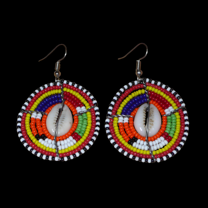 Boucles d'oreilles africaines aux couleurs exotiques et motifs ethniques caractéristiques de l'artisanat traditionnel Massai. Confectionnées au Kenya, elles se composent de perles de rocaille orange et multicolores et de coquillages fixés sur des fils de fer montés en forme de boucliers Massai. Ces boucles d'oreilles de taille moyenne mesurent 6 cm de long et 4 cm de large, et se portent avec des crochets en acier inoxydable sur des oreilles percées.