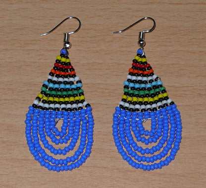 Boucles d'oreilles sud-africaines zouloues en forme de gouttes composées d'un tissage de perles de rocaille bleues et multicolores. Elles mesurent 7 cm de long et 2,5 cm de large et se portent sur des oreilles percées.