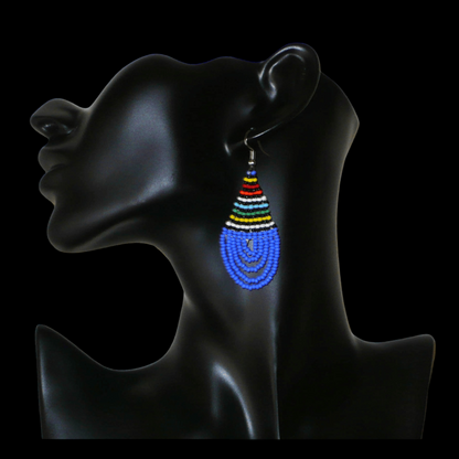 Boucles d'oreilles sud-africaines zouloues en forme de gouttes composées d'un tissage de perles de rocaille bleues et multicolores. Elles mesurent 7 cm de long et 2,5 cm de large et se portent sur des oreilles percées.