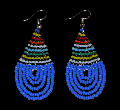 Boucles d'oreilles sud-africaines zouloues en forme de gouttes composées d'un tissage de perles de rocaille bleues et multicolores. Elles mesurent 7 cm de long et 2,5 cm de large et se portent sur des oreilles percées.