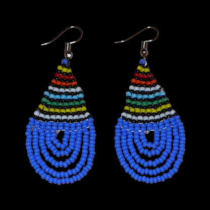 Boucles d'oreilles sud-africaines zouloues en forme de gouttes composées d'un tissage de perles de rocaille bleues et multicolores. Elles mesurent 7 cm de long et 2,5 cm de large et se portent sur des oreilles percées.
